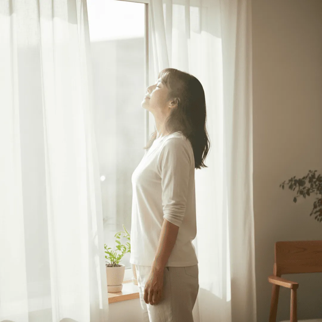 Una mujer abriendo la ventana para respirar aire fresco